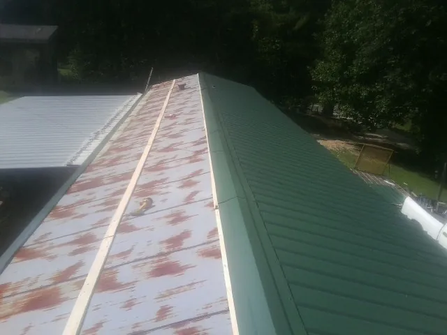 Old rusted panels beside newly installed green metal roofing — Wind Damage Roof Repair by Roofing Brothers in Howard Beach