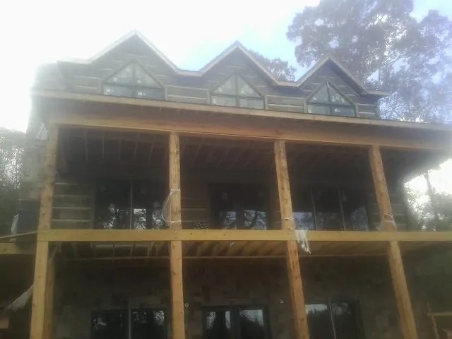 Dormers and porch framing on a large log home under construction — Roof Coating work by our crew in Howard Beach