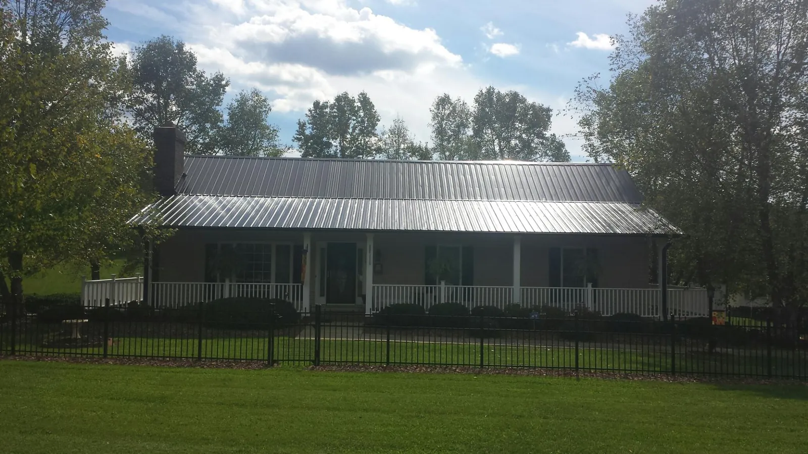Gray metal roof on a brick ranch with a full width front porch — Gutter Guard Installation work by our crew in Howard Beach