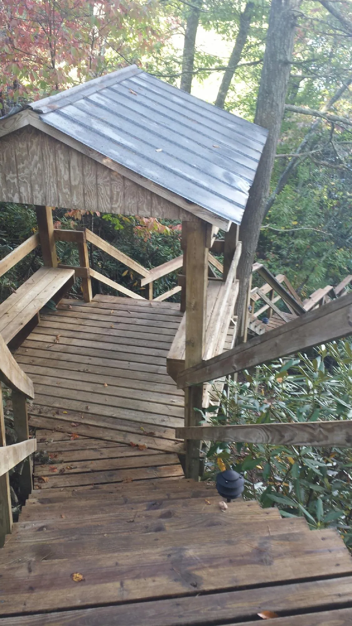 Metal roofed shelter over wooden steps on a wooded walkway — Skylight Repair & Installation work by our crew in Howard Beach