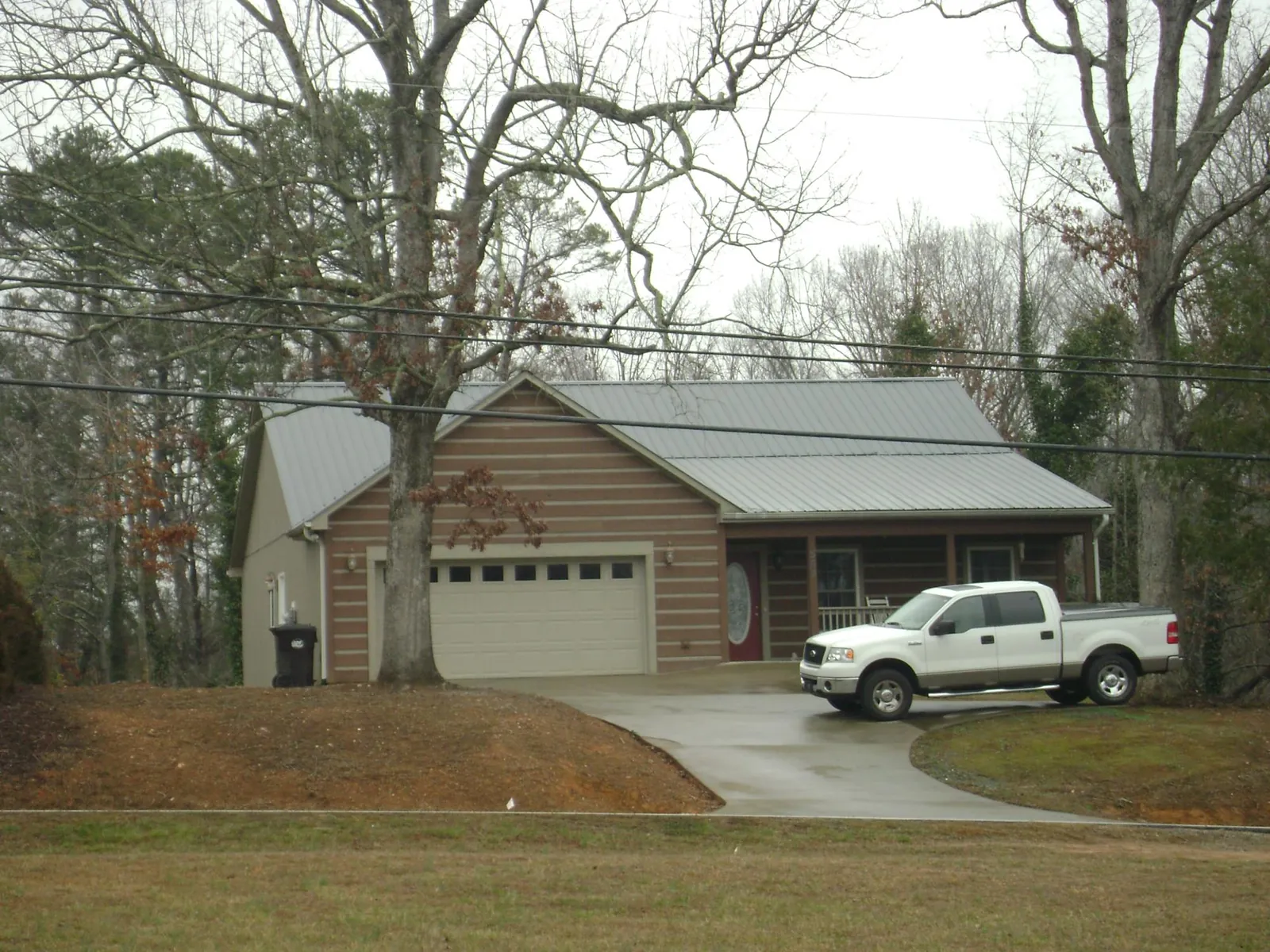 Gray metal roof on a log sided house with an attached two car garage in Howard Beach