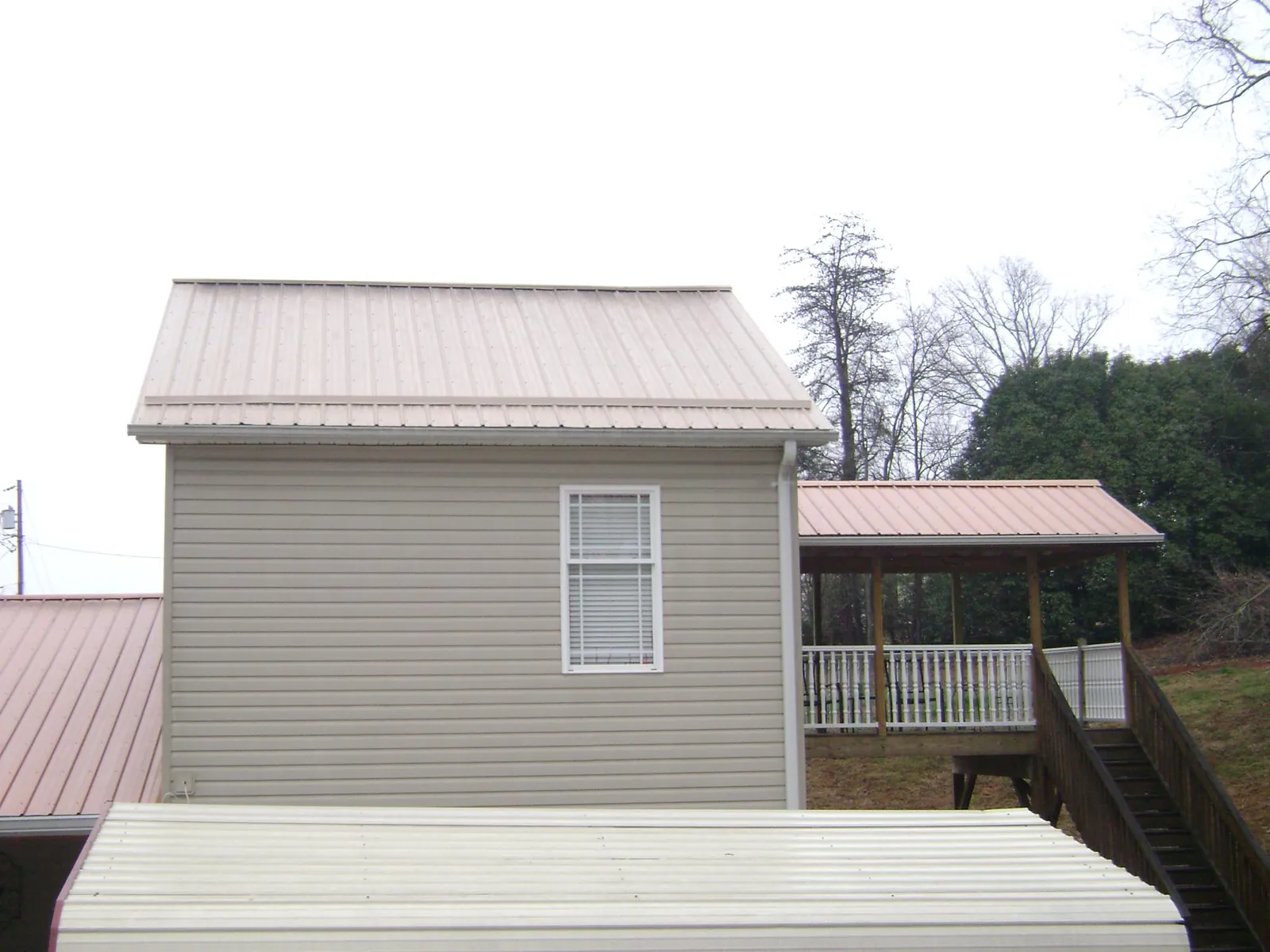 Tan metal roofs on a two story addition and attached porch, from a Roof Replacement job in Howard Beach