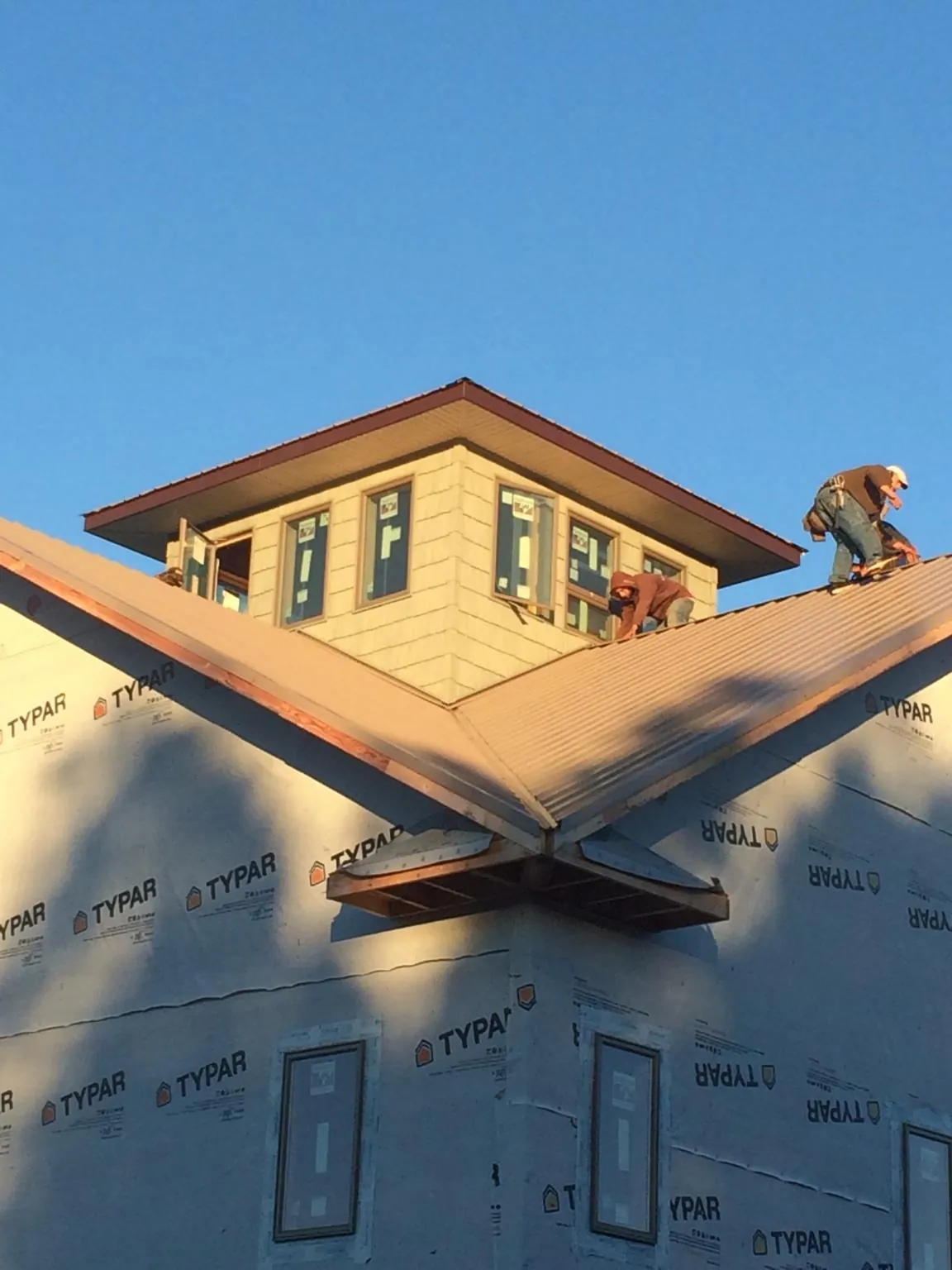 Roofers working around a rooftop cupola on a new metal roof at sunset — Roof Waterproofing in Howard Beach by Roofing Brothers
